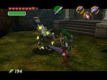 The adult version of Link, armed with a sword and shield and wearing a green tunic, is fighting a bipedal wolf in front of the Forest Temple. Link's fairy companion, Navi, has turned yellow and hovers above the creature which is now surrounded by yellow crosshair-like arrows.