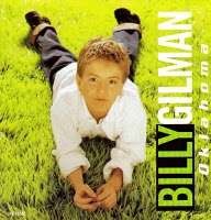 A sunlit grass field shows Billy Gilman on his stomach with his legs up and hands in front of him.