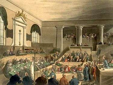 a painting of a large, pillared white room filled with people in the middle of a court case. The view is from the side; an advocate can be seen in a box on the right, while on the left are a panel of judges sitting in front of a curved desk.
