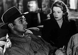A black and white screenshot of Robert Mitchum on the left and Jane Greer on the right in the film Out of the Past