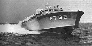a powerboat speeds across the water, riding high so the hull is exposed. "PT 32" is painted on the hull in large white letters.