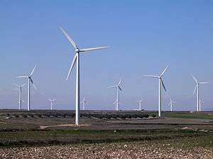 A wind farm of about a dozen three-bladed white wind turbines.