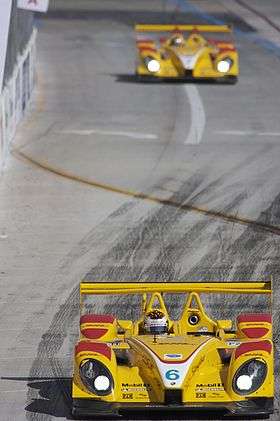 Picture of bright yellow RS Spyder racing car on a race track with another yellow car in the background