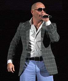 A picture of a man singing wearing a casual suit.