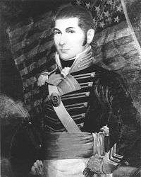portrait of O'Bannon staning in a dress uniform with an American Flag in the backgroun