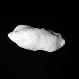 An irregularly shaped oblong body is fully illuminated. It is elongated in the direction from the right to left. Its surface is covered by craters. There is valley at the top.