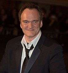 Quentin Tarantino in a suit, smiling