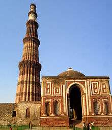 Red and white building with a white dome and a tall tower or minaret with varying cross sections depending on height.