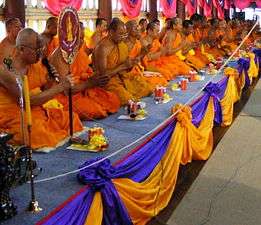 Bhikkhus in saffron robes kneeling in Thailand