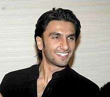 Singh looking towards his left and smiling, wearing a black t-shirt