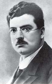 Black-and-white portrait of a mid-aged white man with round glasses, dark curly hair and a moustache