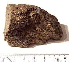 A brown block of irregular shape and surface, about 6 cm in size.
