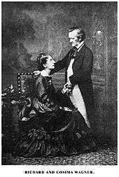 A couple is shown: On the left is a tall woman of about 30. She wears a voluminous dress and is sitting sideways in an upright chair, facing and looking up into the eyes of the man who is on the right. He is about 60, quite short, balding at the temples. He is dressed in a suit with tailcoat and wears a cravat. He faces and looks down at the woman. His hand rests on the back of the chair.