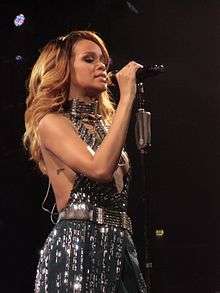 A dark blonde woman wearing a grayish shining outfit is performing