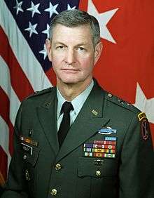 Portrait of a middle-aged white man in a formal military uniform in front of a U.S. flag