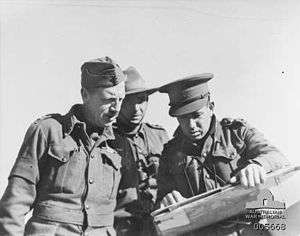 Three warmly dressed men in uniforms look at a map.