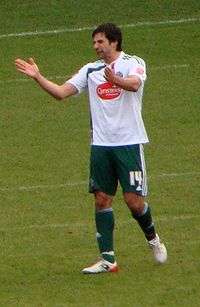 A man wearing a white and green football kit.