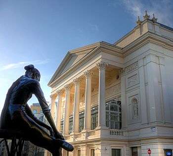 exterior of neo-classical theatre, with a statue outside of a ballerina