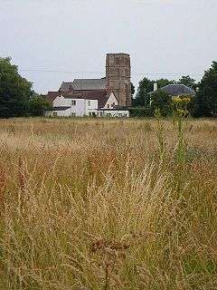 Stone building with square tower showing across fields.