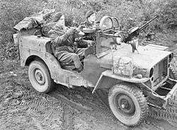 two men in a machine gun armed jeep