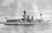 A large gray warship with two tall masts and two thin smoke stacks sits motionless offshore