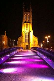 The bridge lit at night with a church in the background