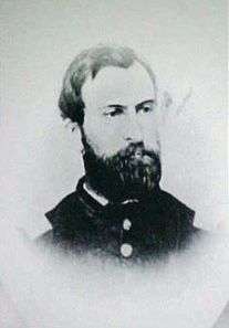 Head of a white man with a full beard and receding hairline, wearing a military jacket with large bright buttons.