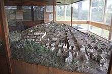 A large table enclosed in glass containing many miniaturized buildings laid out to form a town
