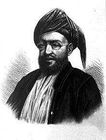 A black-and-white sketch of a man with a dark beard wearing glasses, a turban, a dark jacket, and a white shirt all in front of a white background