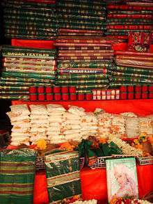 Green and red saris and kumkum on sale in a shop