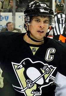 Sidney Crosby in a black home Penguins jersey and black helmet with a clear shield covering his eyes