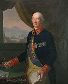 An old, pink-skinned man wears a navy frock coat adorned with medals.