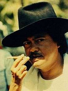 Promotional picture of Sjumandjaja in a hat and holding a cigarette