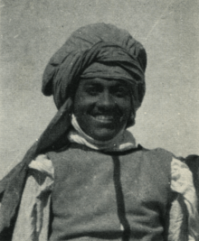 A portrait photograph Ehnni, a dark-skinned man wearing a turban