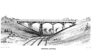 A trestle bridge on four piers spans a cutting over two rail tracks