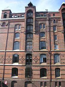 A red brick multi-storey house in Neo-Gothic style with little towers and other ornamental features.