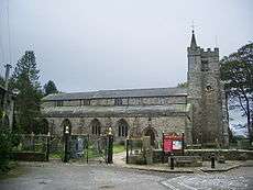 A long church with a clerestory, battlemented tower, and a stair turret with a small spire