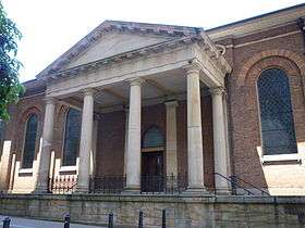 Columns supporting an entablature and pediment extending from the church to create a covered entrance