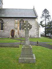 Stone Celtic cross in front of a church