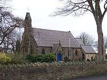 A small stone church with a west bellcote and a lower chancel and vestry