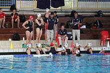 water polo players in and out of water listening to coach