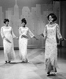 A black and white photo of three women performing on a stage.