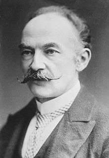 A black and white photograph of Hardy from his late middle age. He is wearing smart, formal clothes, such as a stiff collar and tie. He has a well-tended handlebar moustache