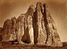 A black and white image of a tall rock wall