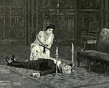  The body of a man lies supine, with a woman, crucifix in hand, kneeling over him. A candle is placed to each side of his head.