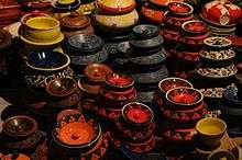 An image showing a number of pots which are made traditionally, black coloured with red and green work on it.