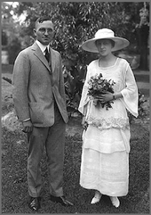 Wedding photo of Truman in gray suit and his wife in hat with white dress holding flowers