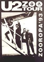 A black poster with a black-and-white image occupying most it. The image shows U2 walking up the stairs of a small aeroplane as Bono gives a peace sign towards the viewer. Text on the poster reads "U2 Zoo TV Tour" and "Zooropa '93".