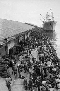 Troops unload supplies from a boat at a pier
