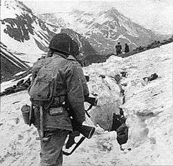 A line of soldiers hiking on the side of a very snowy mountain, viewed from behind
